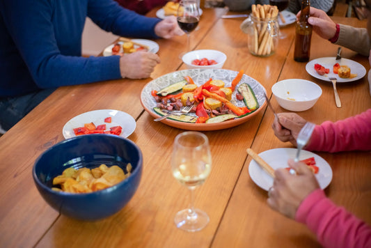 Casual dinner party with friends sharing food and drinks around a wooden table.